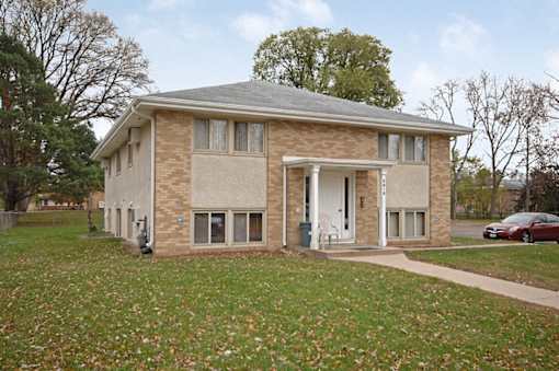 A brick house with a white door and windows.