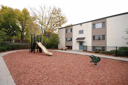 A playground with a slide and a green frog statue.