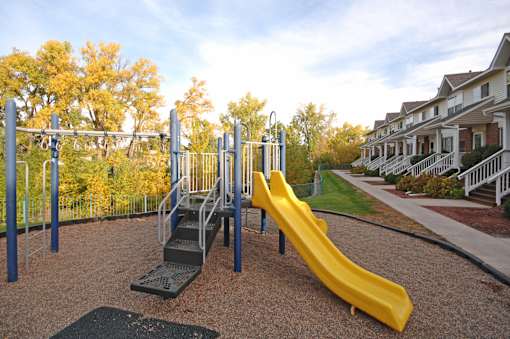 A playground with a yellow slide and a metal structure.