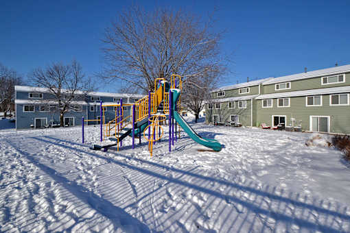 A playground with a yellow and blue slide in the snow.