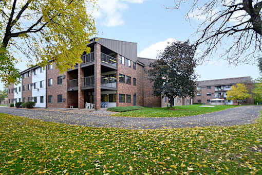 A building with a balcony and a yellow tree in front.