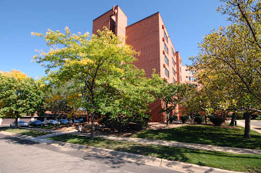 A large red brick building with a tower and trees in front.