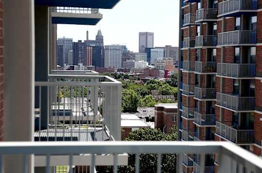 A cityscape is visible from a balcony.