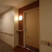 A hallway with a brown door and a light on.