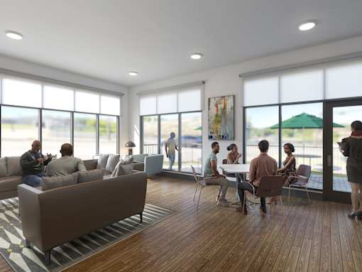 A group of people are gathered in a room with a large window overlooking a green umbrella.