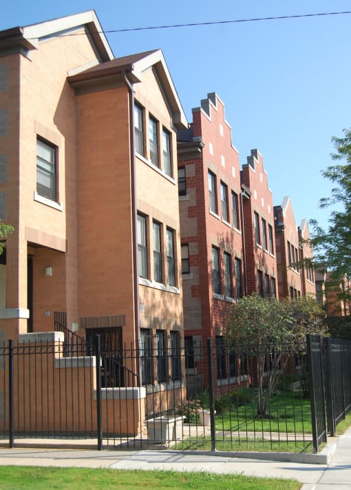 a row of brick apartment buildings with a black fence in front of them
