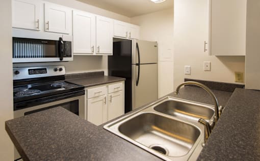 A kitchen with a stove, oven, refrigerator, and sink.