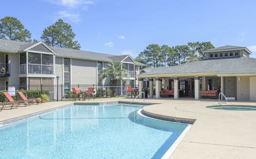 A swimming pool in front of a building with a red chair.
