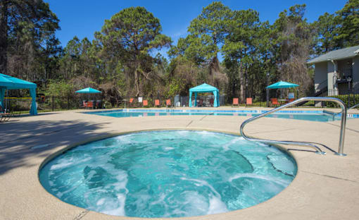 A hot tub in the middle of a pool surrounded by trees.