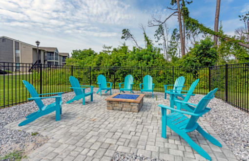 A set of blue chairs are arranged around a fire pit.
