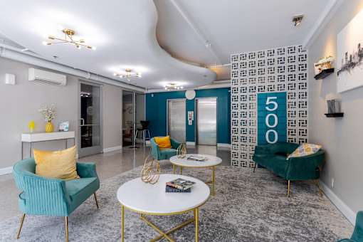 Living room with blue and yellow furniture and a lobby with a 50o sign at 500 Fifth Apartments, Nashville, TN