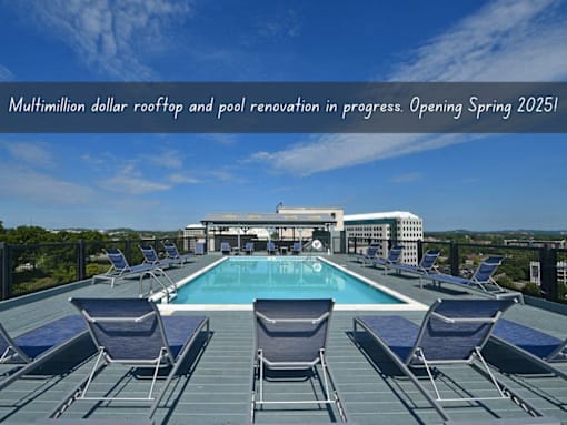 A swimming pool surrounded by lounge chairs on a rooftop.