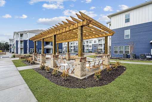A wooden pavilion is in the middle of a grassy area with a building in the background.at The Parker Leland, Leland North Carolina  