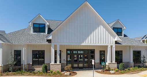 A white building with a black roof and a sign in front at The Ashton at East Park Apartments, Kennesaw, GA, 30144