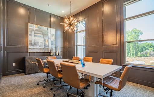 A conference room with a long table and chairs at The Ashton at East Park Apartments, Kennesaw, GA