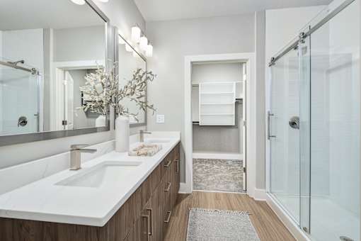 A bathroom with a white sink and a glass shower at The Ashton at East Park Apartments, Kennesaw, Georgia