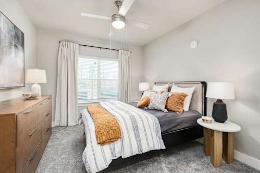 A bedroom with a bed, nightstand, and a painting on the wall at The Ashton at East Park Apartments, Kennesaw, GA