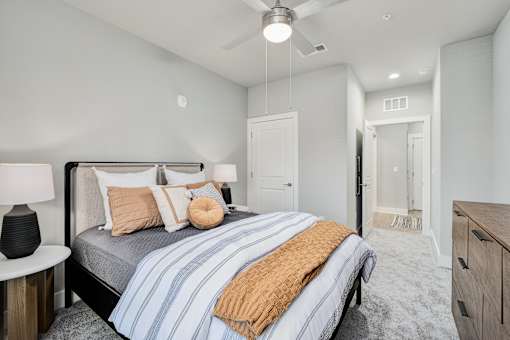 A bedroom with a bed, nightstand, and ceiling fan at The Ashton at East Park Apartments, Kennesaw