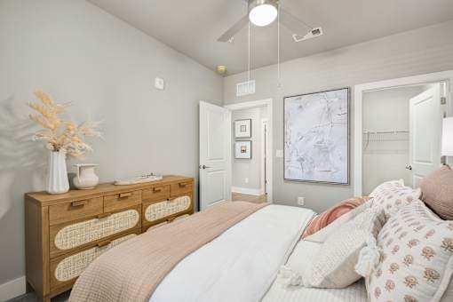 A bedroom with a bed, dresser, and a painting on the wall at The Ashton at East Park Apartments, Kennesaw