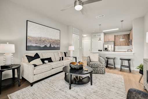 A living room with a large painting on the wall and a white couch at The Ashton at East Park Apartments, Georgia