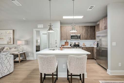 A modern kitchen with a white island and two chairs at The Ashton at East Park Apartments, Kennesaw, GA