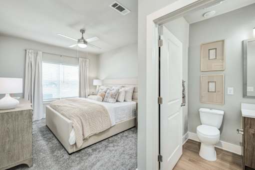 A bedroom with a bed, a toilet, and a mirror at The Ashton at East Park Apartments, Kennesaw, Georgia