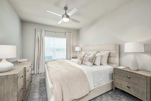 A bedroom with a large bed, two nightstands, and a ceiling fan at The Ashton at East Park Apartments, Georgia, 30144