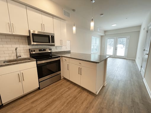 A kitchen with white cabinets and a black microwave at Emery Village, Concord, NC