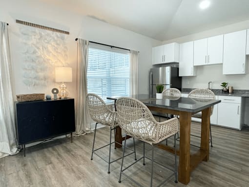 A kitchen with a table and chairs in the foreground and a refrigerator in the background at Emery Village, Concord, NC