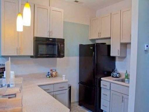 Kitchen with black appliances and white cabinets at Emory Woods Apartments, Durham, NC.