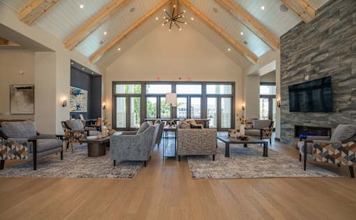 A living room with a stone fireplace and a large TV mounted on the wall at The Ashton at East Park Apartments, Kennesaw, GA, 30144