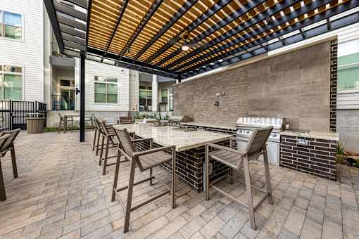 a patio with a table and chairs and a grill at The Monroe Apartments, Austin, TX