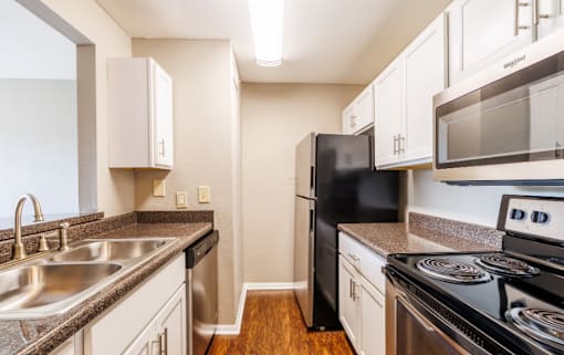 A kitchen with black appliances and white cabinets.