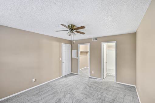 Empty room with a ceiling fan and carpeted floor.