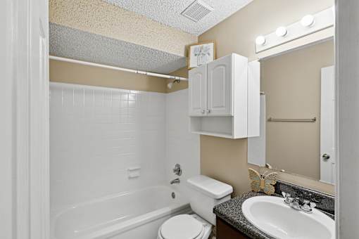 A bathroom with a white tub, toilet, and sink.