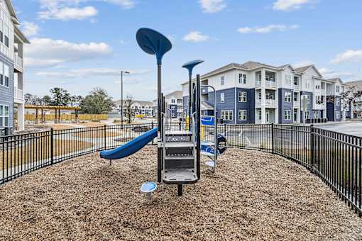 A playground with a blue slide and a black fence.