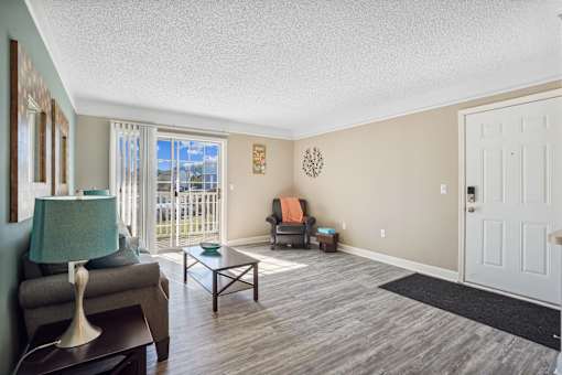 Living room with a couch and a chair and a door to a balcony  at Cape Landing, Myrtle Beach, South Carolina