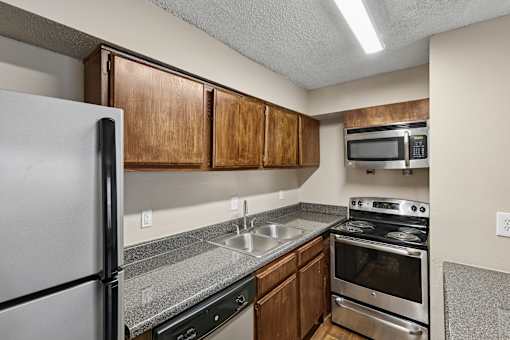 A kitchen with a refrigerator, oven, and microwave.