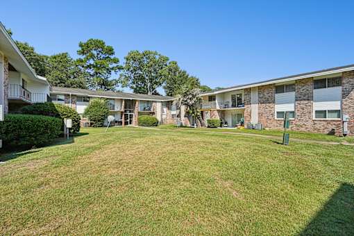 Courtyard area with manicured lawn and mature trees at The Palms Apartments, South Carolina
