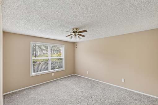 A room with a ceiling fan and a window.