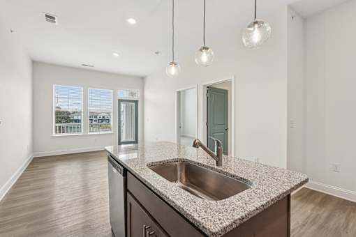 A kitchen with a granite countertop and a stainless steel sink.
