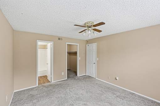 A room with a ceiling fan and carpeted floor.