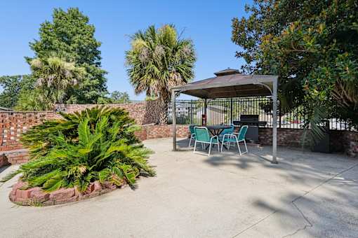 Covered patio area with seating and grill at The Palms Apartments, Charleston, SC
