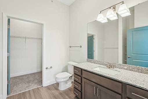 A bathroom with a toilet, sink, and mirror.