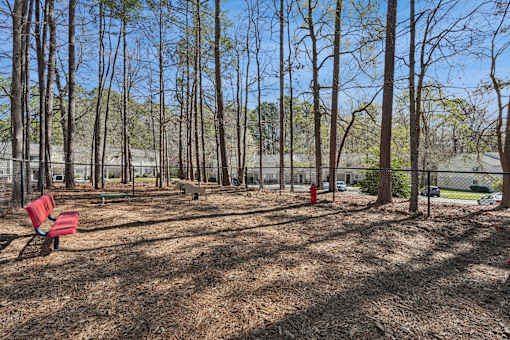 A park with a red bench and a fence.