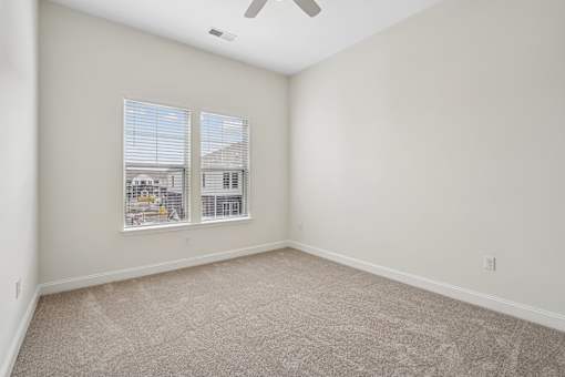 A room with a carpet floor and a ceiling fan.