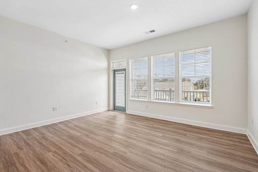 A room with wooden flooring and a door leading to a balcony.