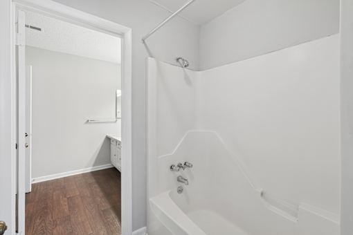 A white bathroom with a tub and a doorway.