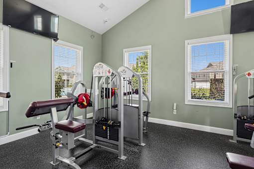 A home gym with a weight bench, barbell, and dumbbells. at The Lory of Greenway Village Apartments, Kentucky