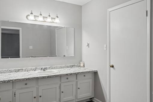 A bathroom with a marble countertop and a large mirror above it.